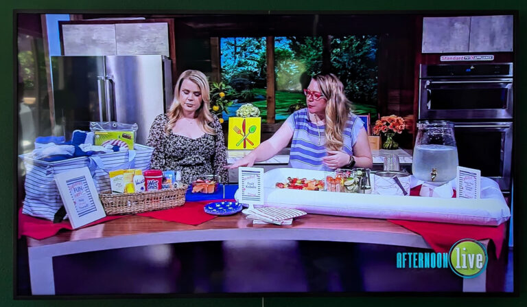 Photo of TV with shot of Hannah the host of Afternoon Live on KATU with Jenni Bost of A Well Crafted Party behind a party set up for a summer pool party