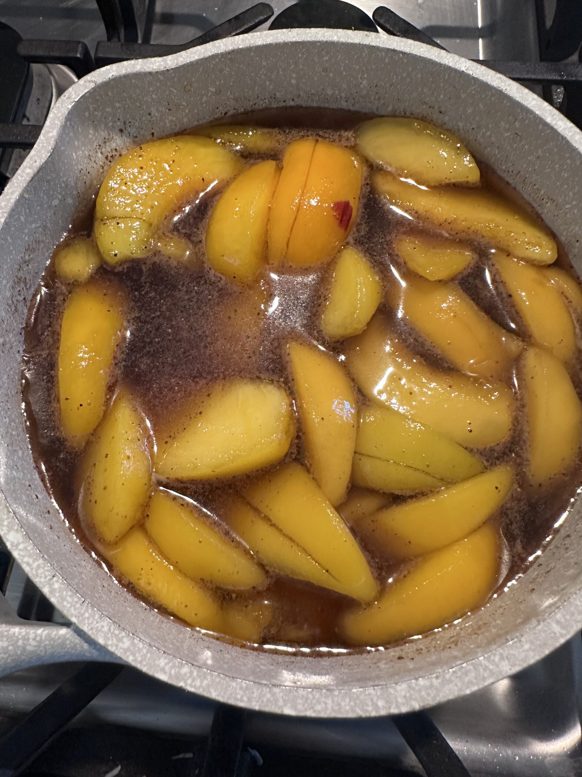 Peaches in brown sugar and water mixture with cinnamon stick