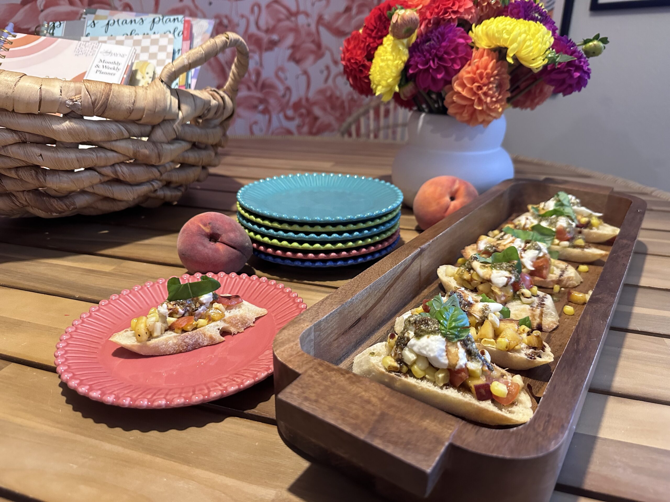 peach and corn appetizer on wood tray with colorful appetizer plates and colorful mum flowers